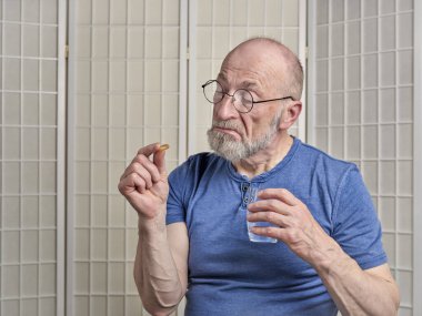 Son sınıf öğrencisi tiksinti ve şüpheyle bakıyor yutmak için ilaç ya da ilaca, kişisel sağlık konseptine.