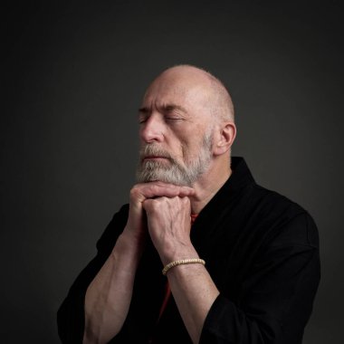 Kafası ve omuzları kel ve sakallı yaşlı bir adamın portresi. Gözleri kapalı. Düşünüyor, meditasyon yapıyor ya da dua ediyor.
