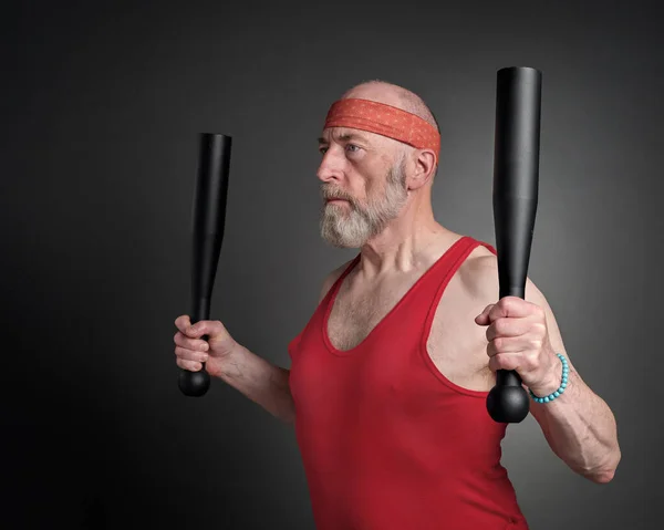 head and shoulder portrait of senior man (in late 60s) exercising with heavy steel clubs,  fitness over 60 concept