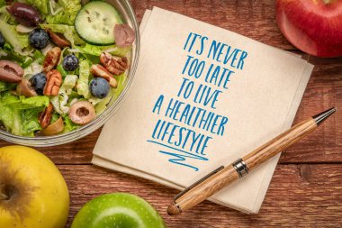 It's never too late to live a healthier lifestyle, inspirational note on a napkin with green salad and apples