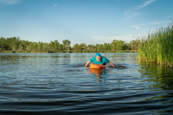 陸上競技 老人はコロラド州の湖でカヤックを漕いでいますこのウォータースポーツはカヤックと水泳の側面を組み合わせています — ストック写真