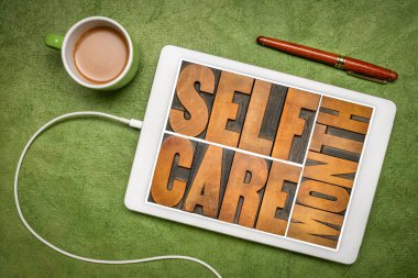 self care month - word abstract in letterpress wood type on a digital tablet, flat lay with coffee, reminder of annual event (September)