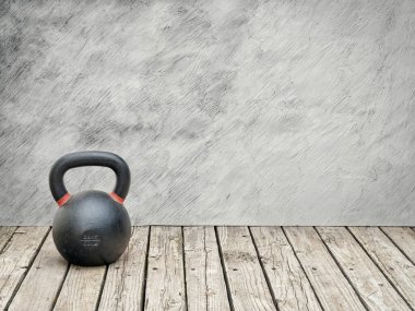 Kırsal bir ahşap zemin üzerinde demir kettlebell Bir kopya alanı ile grunge duvar karşı