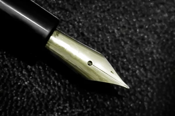 Close up of a old pen on a black leather book — Stock Photo, Image