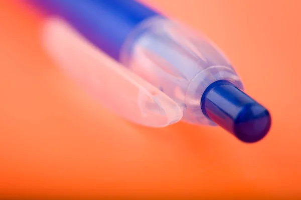 Foto de un bolígrafo azul en cuaderno naranja — Foto de Stock