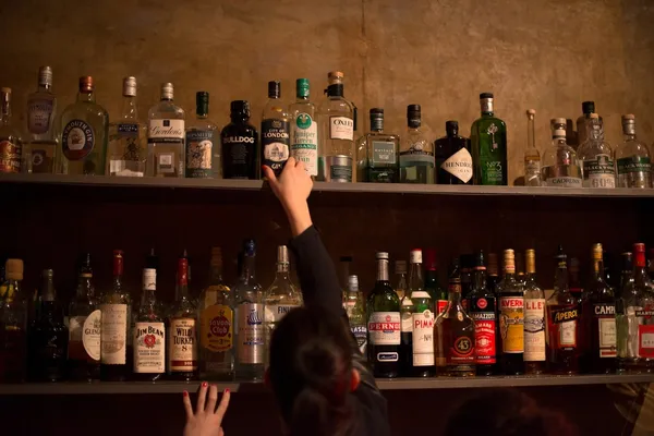 アルコール飲料のびんのウェイトレスとバーの棚 — ストック写真