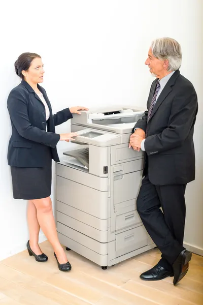 Коллеги разговаривают за копировальной машиной в офисе — стоковое фото