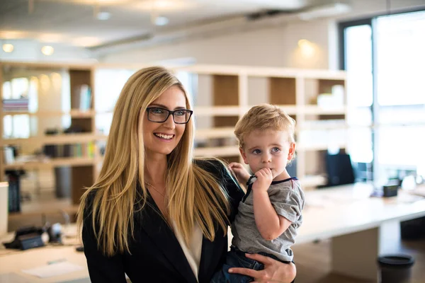 Mujer de negocios con un niño pequeño en la oficina — Foto de Stock