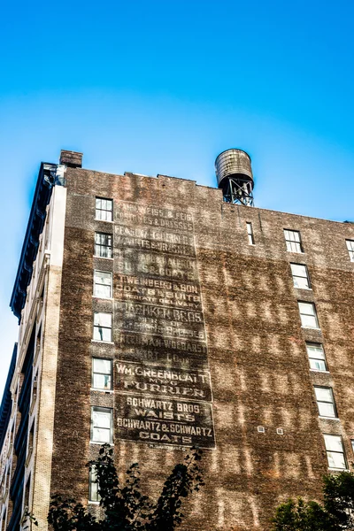 Edifício urbano antigo com lista de antigas marcas em Nova Iorque — Fotografia de Stock