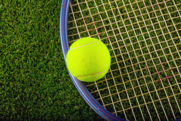 Tennis ball and racket over grass