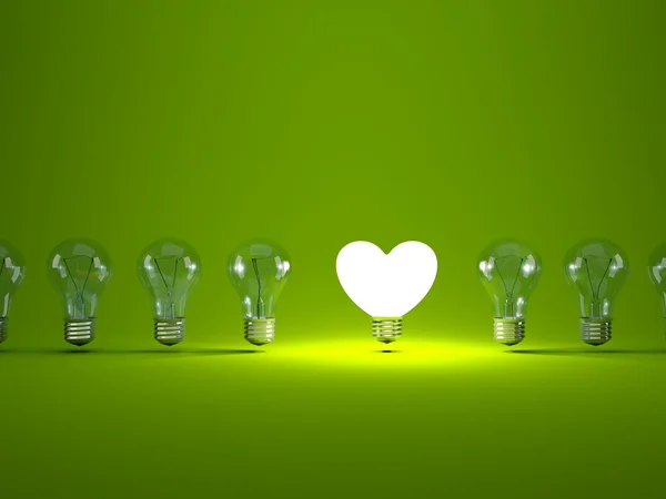 Heart shaped light bulb on green background — Stock Photo, Image