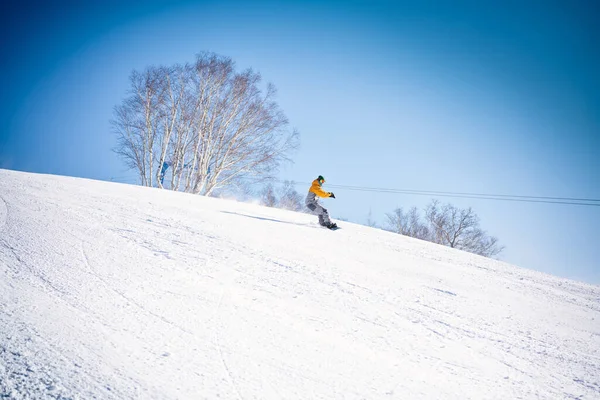 Snowboarder Jadący Dół Wzgórza Przed Błękitnym Niebem — Zdjęcie stockowe