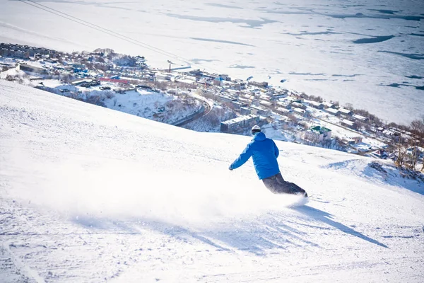 Snowboarder Jadący Dół Wzgórza Przed Lodowatym Oceanem — Zdjęcie stockowe