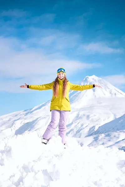 Fröhliche Snowboarderin Gelber Jacke Vor Verschneiten Bergen Und Blauem Himmel lizenzfreie Stockbilder