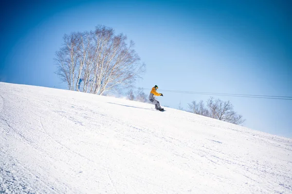 Snowboardåkare Rider Nerför Kullen Framför Blå Himmel Stockbild