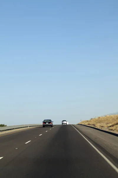 Dwa samochody, idąc w dół autostrady międzystanowej z błękitnego nieba — Zdjęcie stockowe