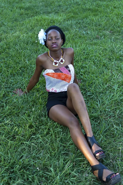 Νεαρή μαύρη γυναίκα κάθεται στο γρασίδι πάρκο — Φωτογραφία Αρχείου