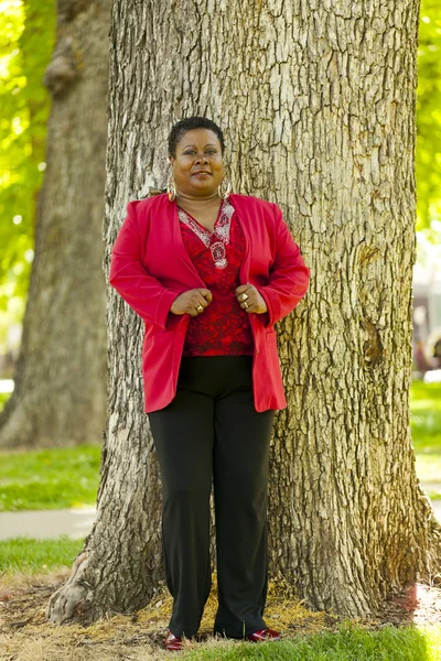 Ältere schwarze Frau steht draußen rote Jacke — Stockfoto
