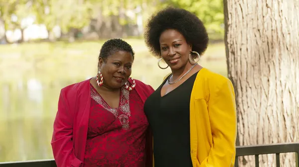 Két idősebb fekete nő kültéri álló piros-sárga — Stock Fotó
