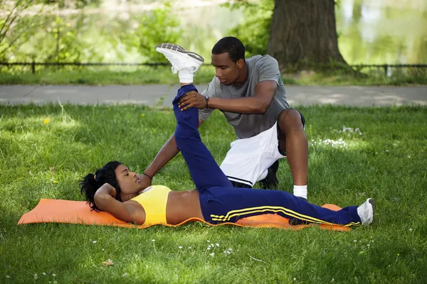 Pareja negra haciendo ejercicio en el parque sobre hierba — Foto de Stock