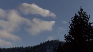 Time Lapse Clouds Coming In Over Hills With Light Snow And Foreground Tree