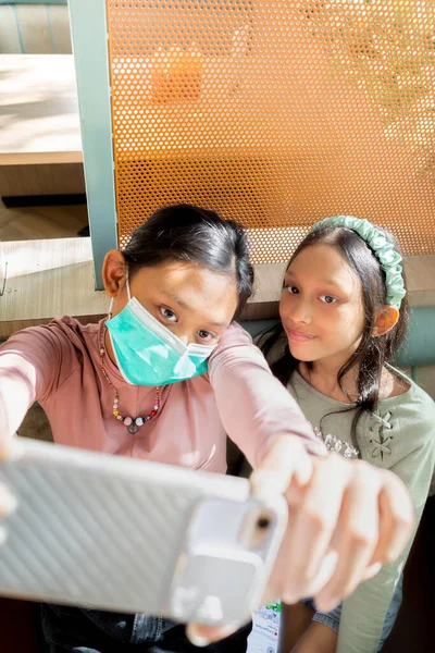 Southeast Asian Teenage Girl Wear Face Mask Doing Selfie Together — стоковое фото