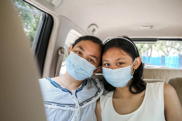 Happy Cheerful Asian Teen Girl and Mother Wearing Mask in Vehicle