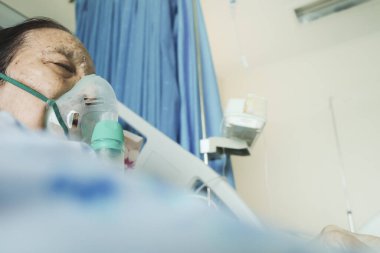 Asyalı kadın kıdemli hasta hastane yatağında nebulizatör kullanılarak hastaneye kaldırıldı ve solunum tedavisi altına alındı.