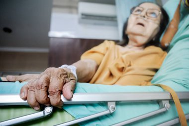 Sick Southeast Asian female senior patient with respiratory disorder having bedrest in hospital