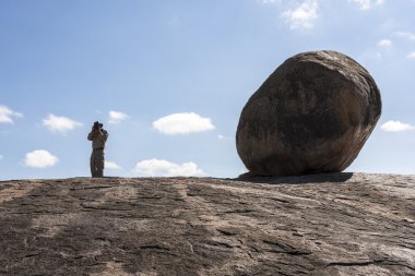 adam bir kayada duran ve fotoğraf çekimi