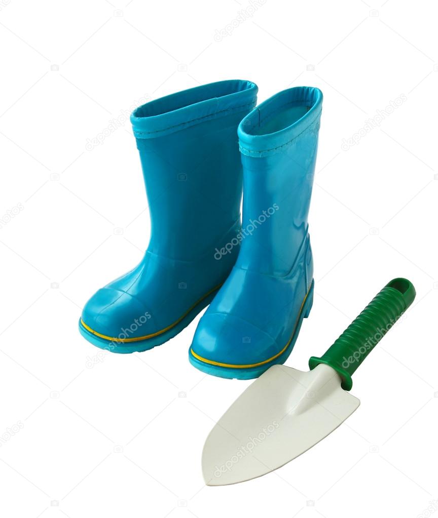 Child's little blue rubber gumboots with a shovel