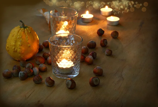 Férias de colheita. Abóbora, avelã e velas em vidro à noite — Fotografia de Stock