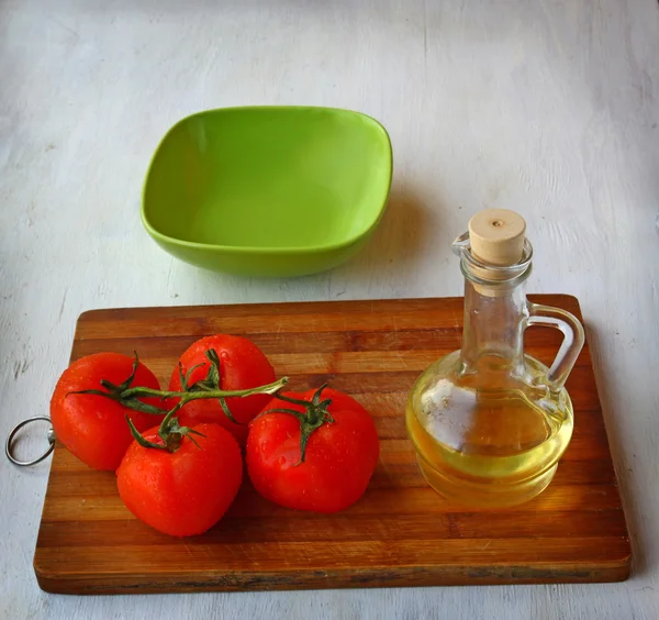 Prázdná mísa na salát a rajčata vedle láhev olivového — Stock fotografie