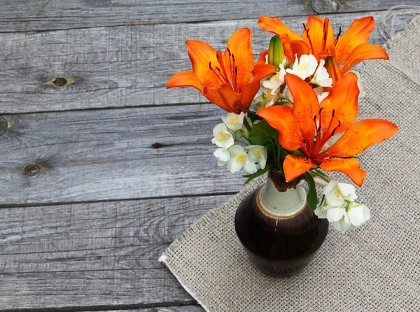 Orange saffran liljor och jasmin blommor på träbord — Stockfoto