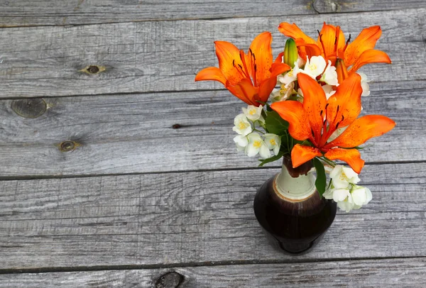 Orange saffran liljor och jasmin blommor på träbord — Stockfoto
