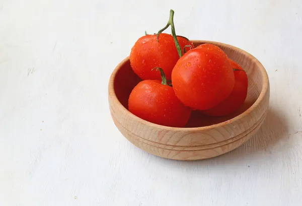 A branch of tomatoes in a wooden bowl — Stock Photo, Image