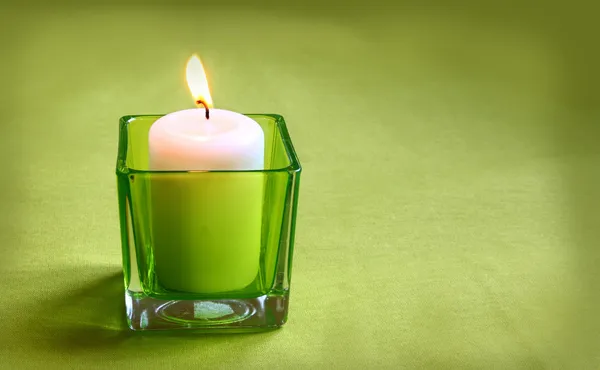 Una vela en lámpara de vidrio sobre un fondo verde —  Fotos de Stock