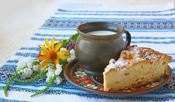Portion of cake with curd next to a glass of milk