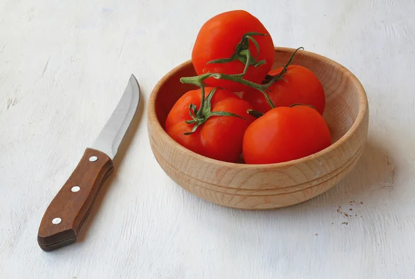 Tomato in a wooden bowl and knof — Stock Photo, Image