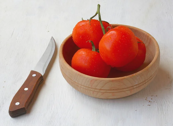 A branch of tomatoes in bowl and knof — Stock Photo, Image