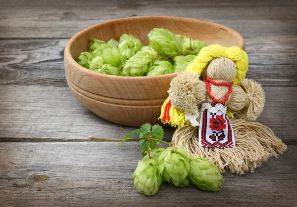 Muñeca motanka de hilo y un tazón de lúpulo recién cosechado — Foto de Stock