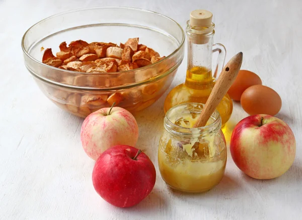 Manzanas al horno y frescas, miel, huevos, aceite en la mesa de la cocina. — Stockfoto