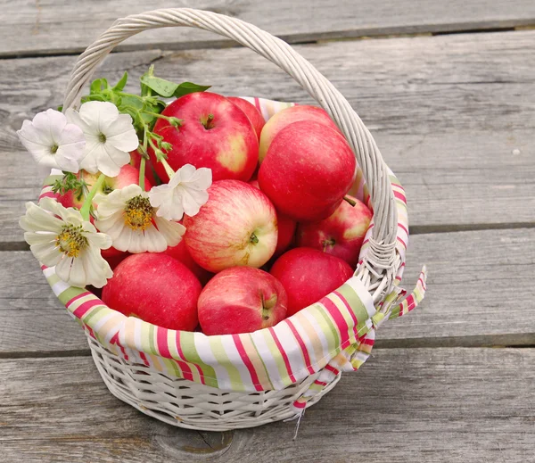 Basket with apples and bunch of flowers — Stock Photo, Image