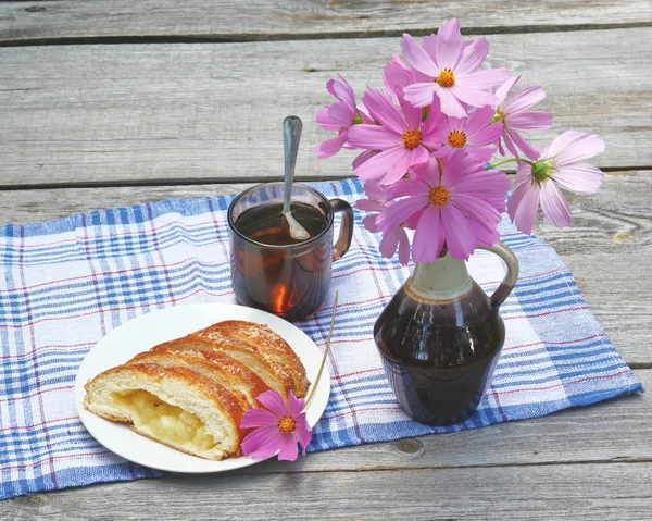 Strudel with apples and a cup of tea next to a bouquet of cosmo — Stock Photo, Image