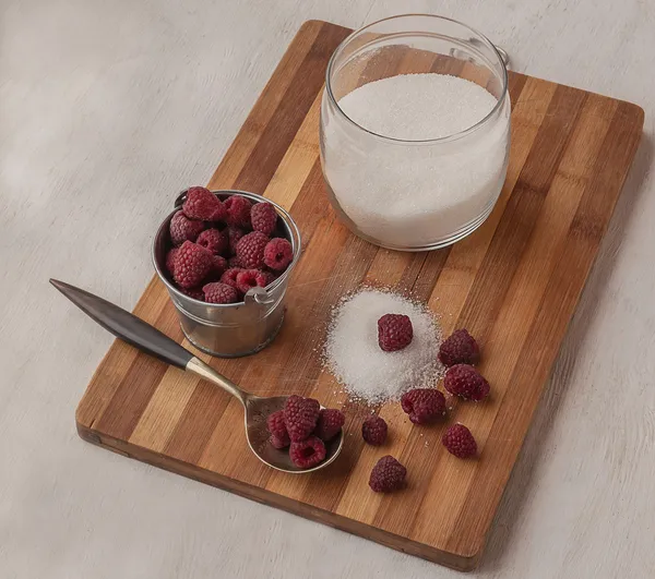 Harvest raspberries and sugar on a cutting board — Stock Photo, Image