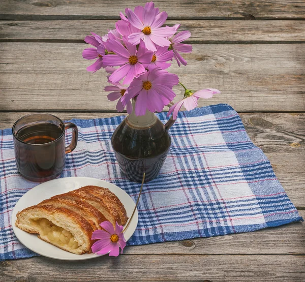 Rétes alma és egy csésze tea mellett egy-egy csokor cosmos — Stock Fotó