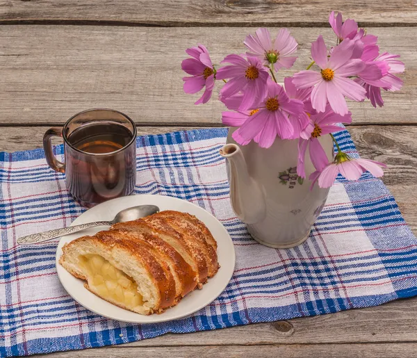 Strudel aux pommes et une tasse de thé à côté d'un bouquet de cosmos — Photo