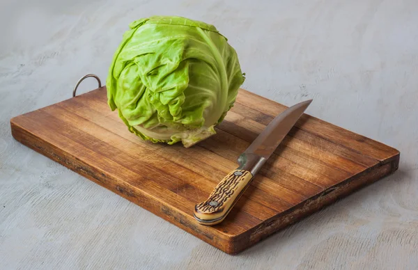 Repollo y un cuchillo sobre una tabla de cortar de cocina — Foto de Stock