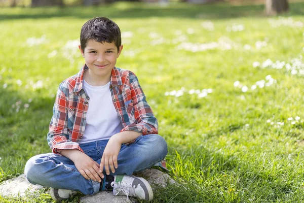 Χαρούμενο Πορτρέτο Αγόρι Κάθεται Στο Γρασίδι Του Πάρκου Της Πόλης — Φωτογραφία Αρχείου