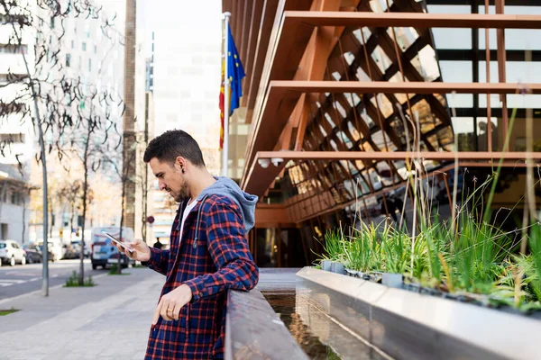 Junger Mann Mit Schal Lehnt Bei Smartphone Nutzung Freien Metallzaun — Stockfoto